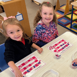 Happy children playing a game at a table and smiling at camera